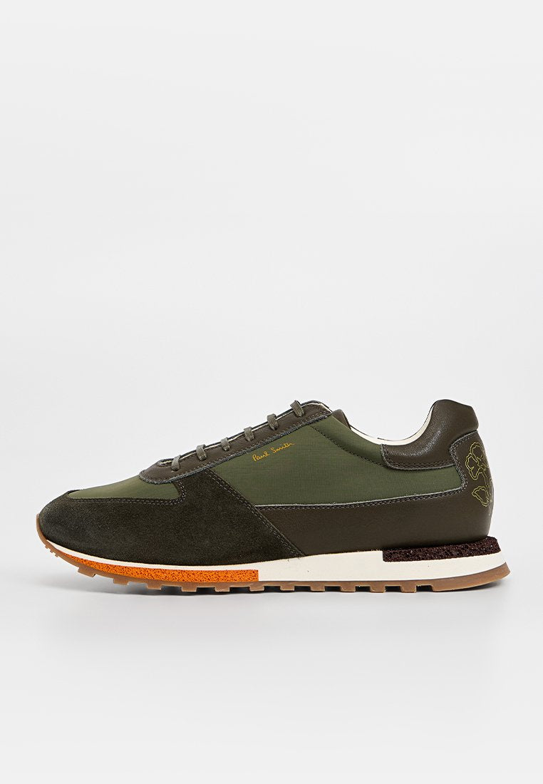 Dunkelgrüne Sneakers aus einer Mischung aus Wildleder und Textil, mit weißer Zwischensohle, orangefarbenen Akzenten und dekorativen Nähten.