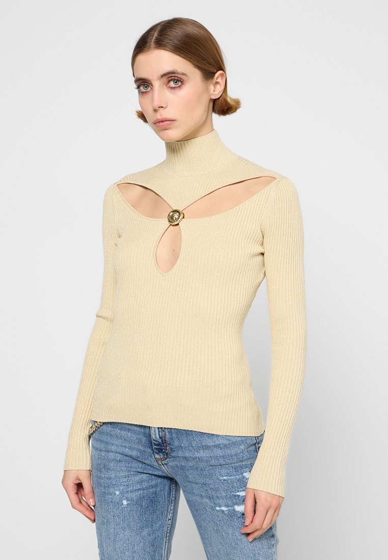 Beige gerippter Rollkragenpullover mit Cut-Out-Details und einem dekorativen goldenen runden Akzent auf der Brust. Enganliegendes Design, lange Ärmel.