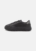 Schwarze Sneaker mit einem glatten Lederobermaterial, runder Zehenform, sechs Metallösen und einer dicken Gummisohle mit strukturierter Oberfläche. Silberner Absatzakzent.