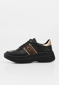Schwarzer Sneaker mit dicker Sohle, braunem Seitenstreifen mit goldenem Hufeisen-Detail, goldenem Fersenakzent und schwarzen Schnürsenkeln.