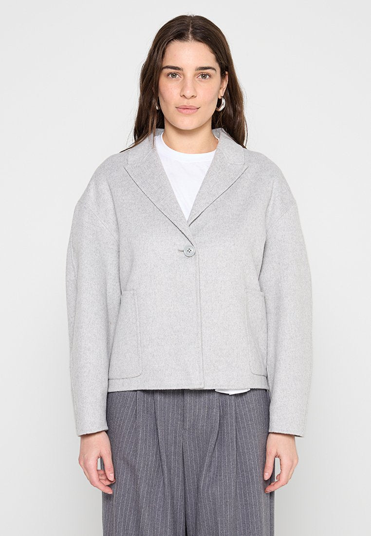 Graue Wollmischungjacke mit einem Reverskragen, einfühlsamen Knopfverschluss und zwei Fronttaschen. Boxy-Form mit herunterhängenden Schultern und weicher Textur.