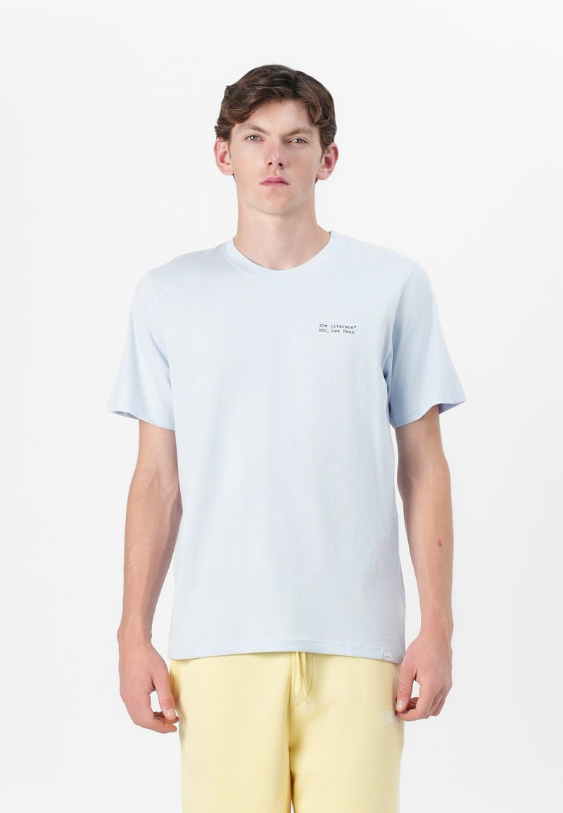 Helles blaues Baumwoll-T-Shirt mit kurzen Ärmeln, einem runden Ausschnitt und einem kleinen gedruckten Logo auf der Brust. Weicher Stoff, lässige Passform.