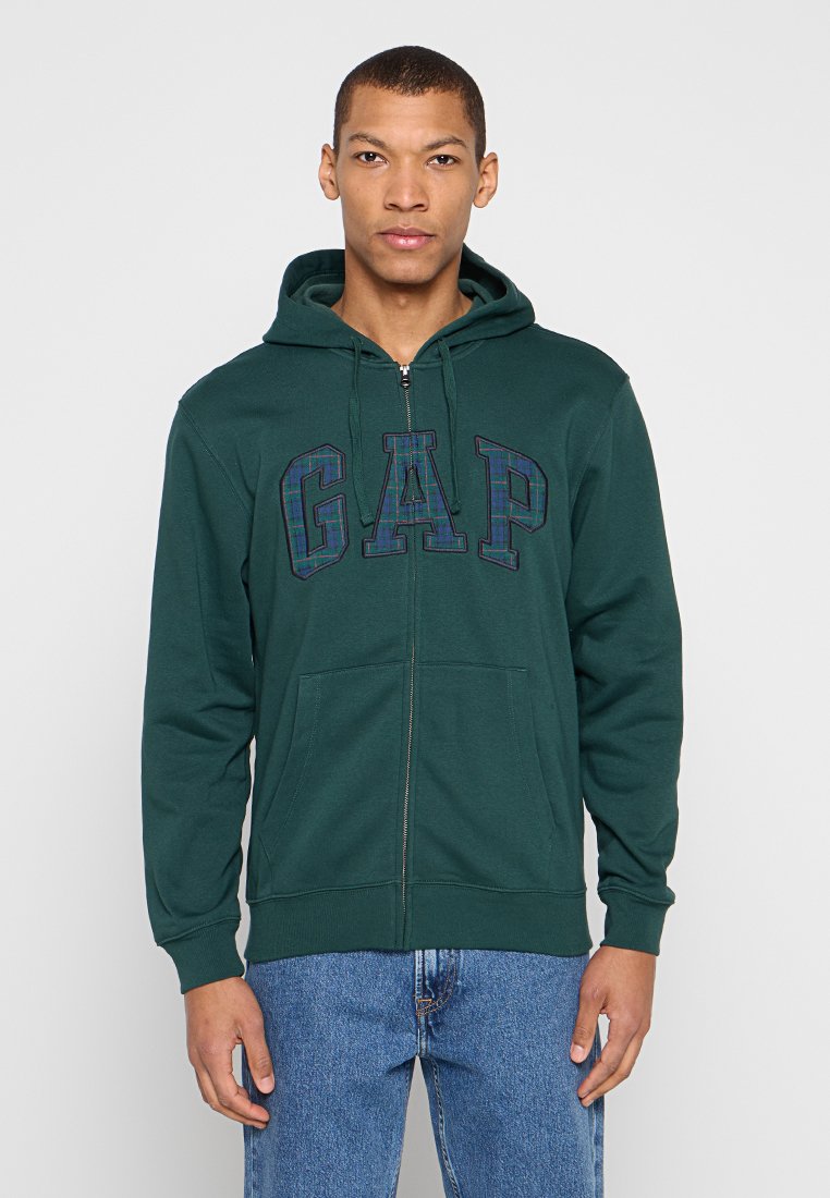 Grüner Zip-Up-Hoodie aus weichem Stoff, mit Frontreißverschluss, Kapuze und großem kariertem "GAP"-Logo. Zwei Fronttaschen und gerippte Ärmelbündchen.