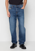 Lässige blaue Jeans mit einem ausgewaschenen Finish, Fünf-Taschen-Design, orangefarbenen Nähten und einem Knopfverschluss. Kombiniert mit polierten schwarzen Schuhen.