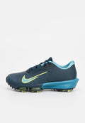Dunkelblaue Nike Sportschuh mit einem strukturierten Mesh-Obermaterial, neon-gelbem Swoosh, hellblauen Akzenten und einer dicken Sohle mit grünen Details.