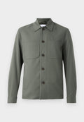 Dunkelgrüne Jacke mit umgeschlagenem Kragen, Knopfverschluss und zwei Brusttaschen. Glattes Gewebe mit tailliertem Schnitt. Die Knöpfe sind braun.