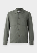 Dunkelgrüne Jacke mit umgeschlagenem Kragen, Knopfverschluss und zwei Brusttaschen. Glattes Gewebe mit tailliertem Schnitt. Die Knöpfe sind braun.