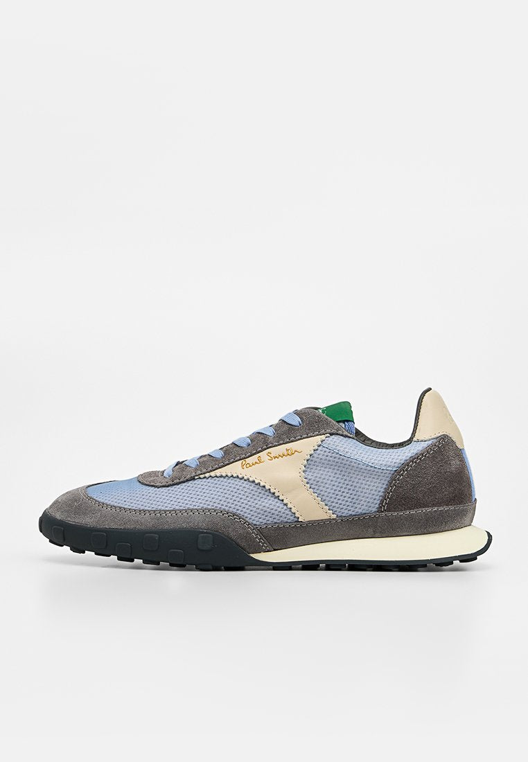 Seitenansicht eines lässigen Sneakers mit blauem Mesh, grauen Wildlederüberzügen, cremefarbenen Akzenten und grünem Zungen-Detail auf weißem Hintergrund.