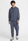 Marineblaue Kapuzenpullover mit einer Kängurutasche, kombiniert mit passenden Jogginghosen. Mit einem Nike-Logo auf der Brust und gemusterten Schuhen.