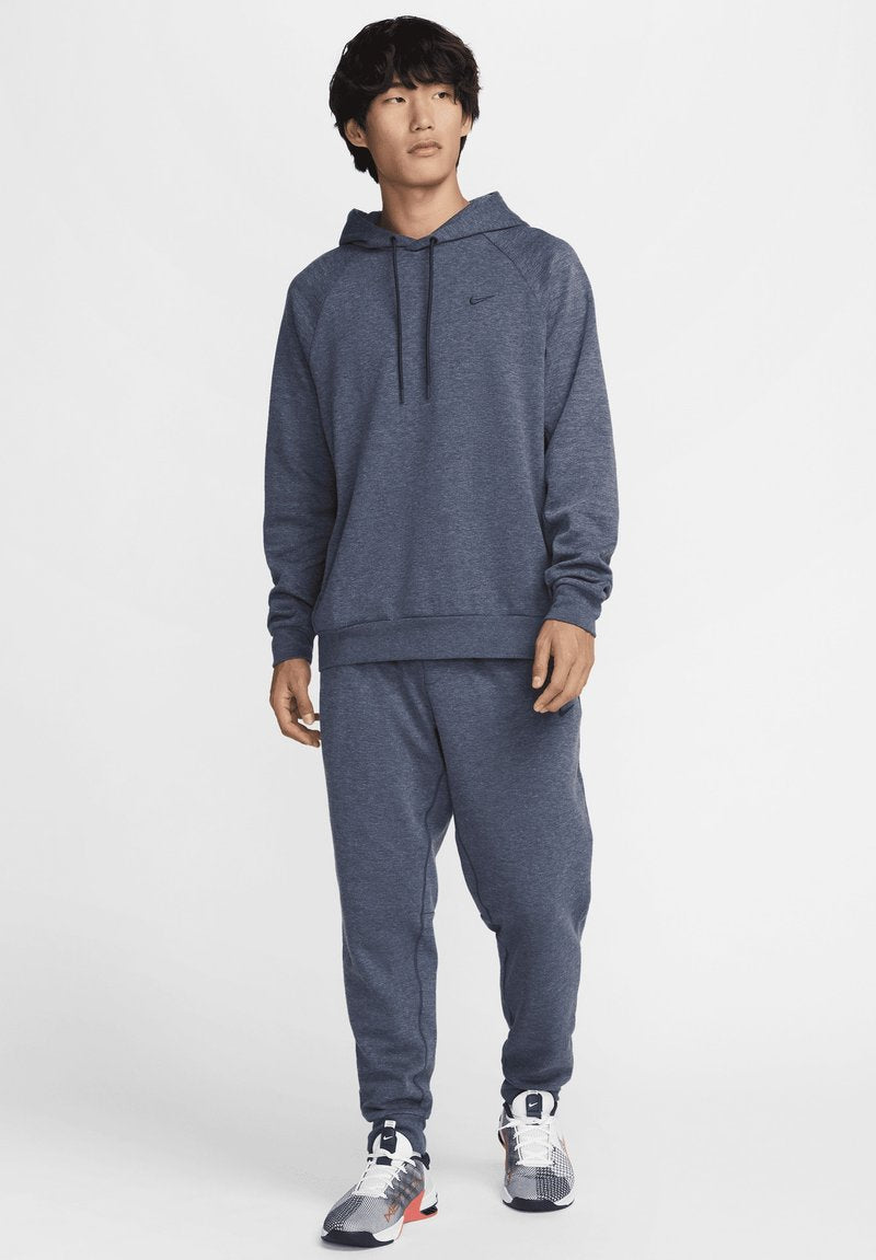 Marineblaue Kapuzenpullover mit einer Kängurutasche, kombiniert mit passenden Jogginghosen. Mit einem Nike-Logo auf der Brust und gemusterten Schuhen.