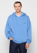 Hellblaues Zip-Hoodie aus strukturierter Stoff, mit einer Kordelzugkapuze und einem kleinen Logopatch auf der linken Brust. Lockere Passform.