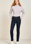 Helllilafarbenes, geripptes Rollkragensweatshirt, kombiniert mit dunkelblauen Skinny Jeans, die eine hohe Taille und zwei dekorative Knöpfe vorne haben.