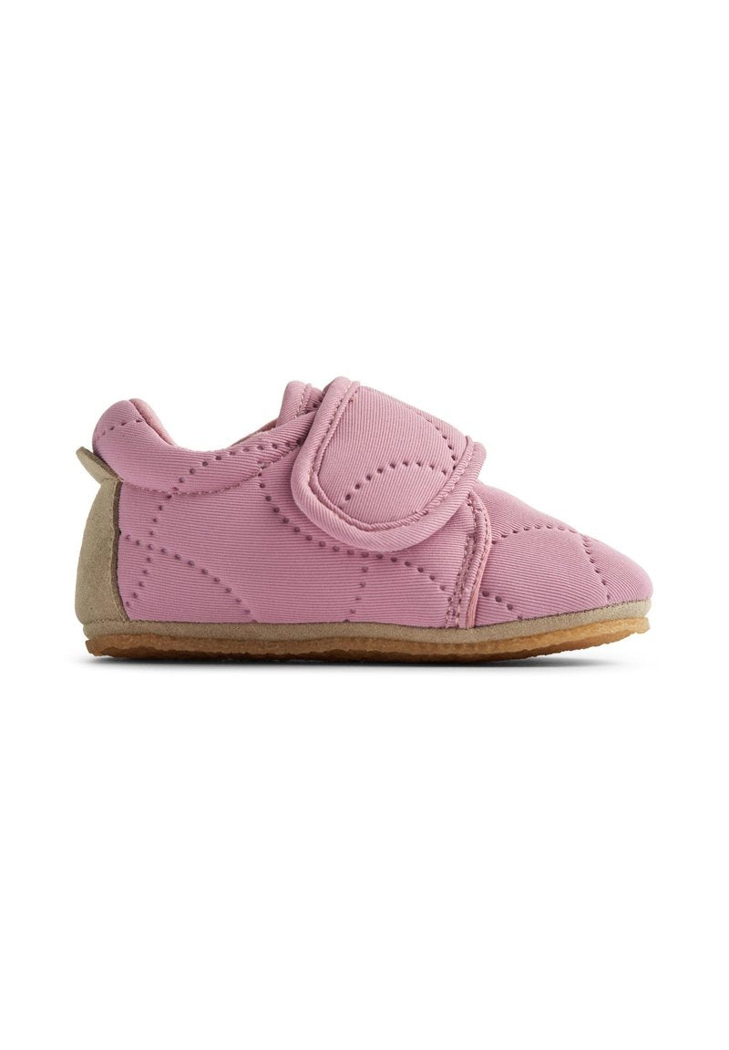 Rosa Stoffschuh mit einem Klettverschluss, gepolstertem, gestepptem Design, weicher, wildlederähnlicher Sohle und runder Zehenform für Komfort und angenehmes Tragen.