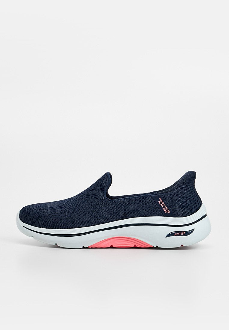 Marineblauer Skechers Sportschuh zum Hineinschlüpfen mit weißer Sohle, pinker Bogenpolsterung und strukturiertem Strickobermaterial.
