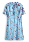 Kurzärmliges, hellblaues Kleid mit floralem und fruchtigem Muster. Es verfügt über einen gerafften Ausschnitt mit einer Schnürung und hat eine lockere Passform.