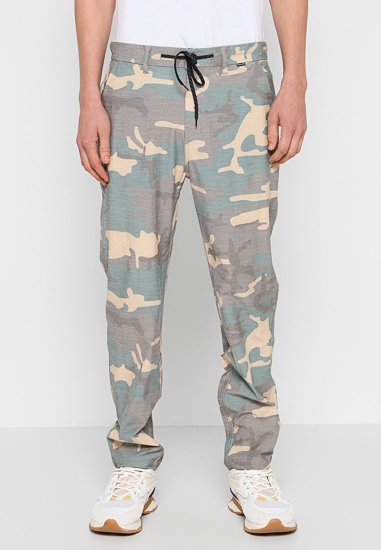 Tarnhosen in hellem Beige und gedämpftem Türkis, aus leichtem Material gefertigt. Sie verfügen über einen elastischen Bund mit Kordelzug und Seitentaschen.