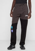 Schwarze und dunkelgraue Jogginghosen mit gerippten Bündchen, elastischem Bund und bestickten Patches in Blau und Lila am linken Bein.