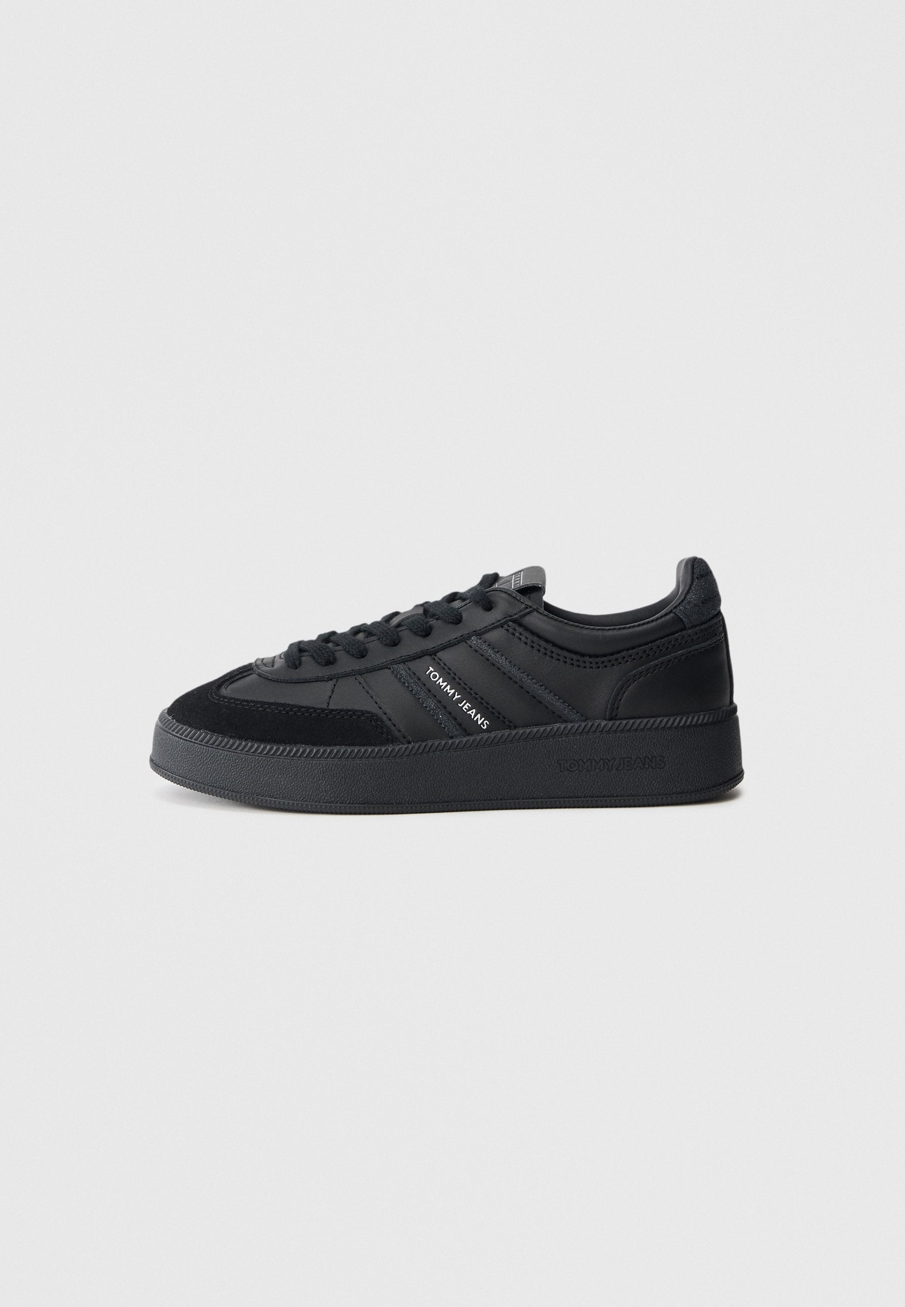 Schwarze Sneaker aus Leder und Wildleder mit dicker Sohle, Schnürsenkeln und markanten Seitenstreifen. Glatte Oberfläche mit strukturierten Akzenten.