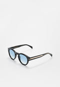 Schwarze runde Sonnenbrille mit blauen Verlaufsgläsern und feinem goldfarbenem Streifendetail an den Bügeln, auf einer weißen Oberfläche präsentiert.