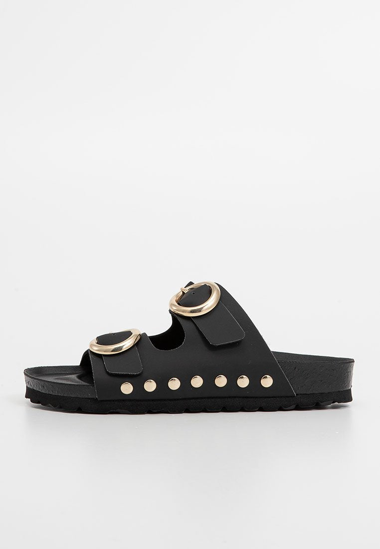 Schwarze Slide-Sandalen aus synthetischem Material mit zwei runden goldenen Schnallen, dekorativen goldenen Nieten entlang der Sohle und einem strukturierten Fußbett.