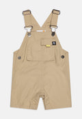 Hellebeige Latzhose aus Baumwolle mit verstellbaren Trägern, Druckknopf-Akzenten, einer Fronttasche und einer lockeren Passform, die ein offenes Bein-Design aufweist.