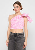 Ein einseitig tragendes pinkes Crop-Top mit einem gebundenen Akzent und einem weichen, strukturierten Muster. Kombiniert mit hoch taillierten dunklen Jeans.