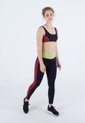 Schwarzer Sport-BH mit roten und grünen Akzenten; hochtaillierte schwarze Leggings mit rotem Seitenstreifen. Model trägt schwarze Sportschuhe.