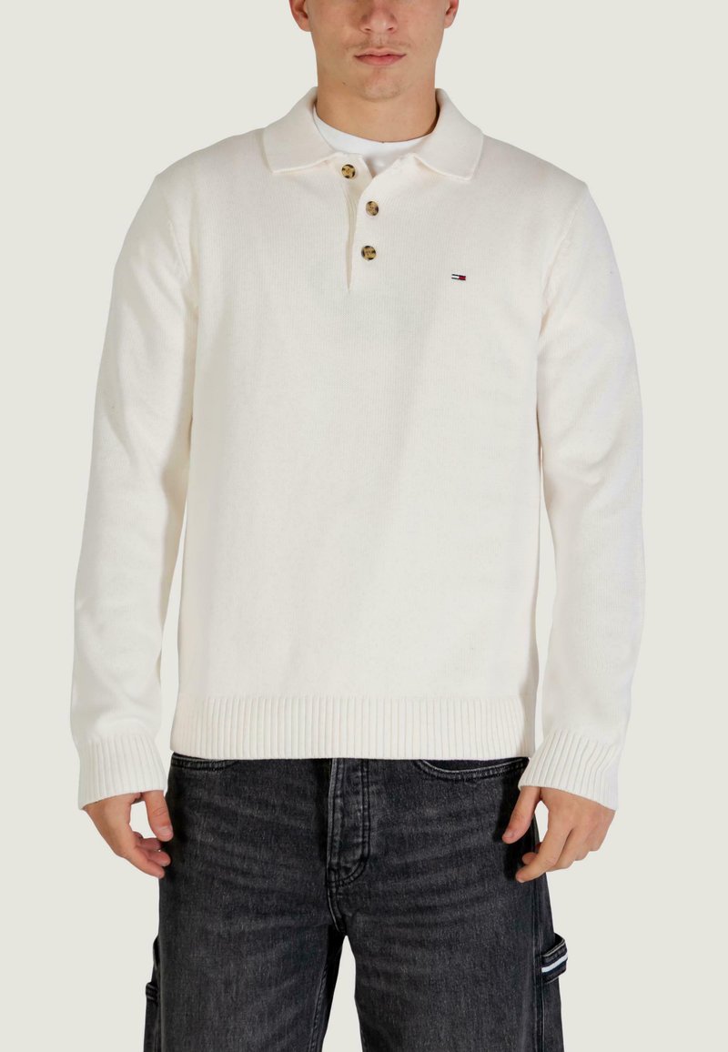 Weißer Strick-Poloshirt mit gerippten Bündchen und Saum, ausgestattet mit drei Knöpfen und einem kleinen Logo auf der Brust. Trägt man zusammen mit dunklen Jeans.