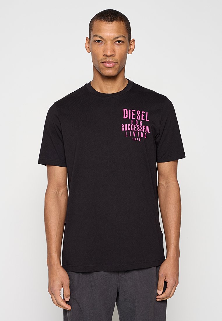 Schwarzes Baumwoll-T-Shirt mit kurzen Ärmeln und Rundhalsausschnitt, mit leuchtend pinkem Grafiktext auf der Brust. Klassische Passform, glatte Textur.