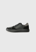 Schwarze Sneaker aus einer Mischung von strukturiertem Leder und Wildleder, mit runder Zehenpartie, flacher schwarzer Sohle und schwarzen Schnürsenkeln. Dezente graue Akzente.