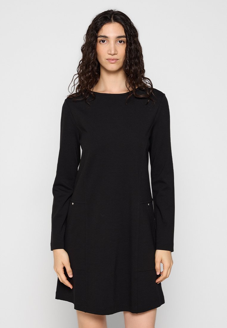 Schwarzes langärmliges Kleid mit rundem Ausschnitt, zwei seitlichen Taschen und einem leicht ausgestellten Saum. Hergestellt aus glattem, weichem Stoff, mit minimalen Hardwareakzenten.