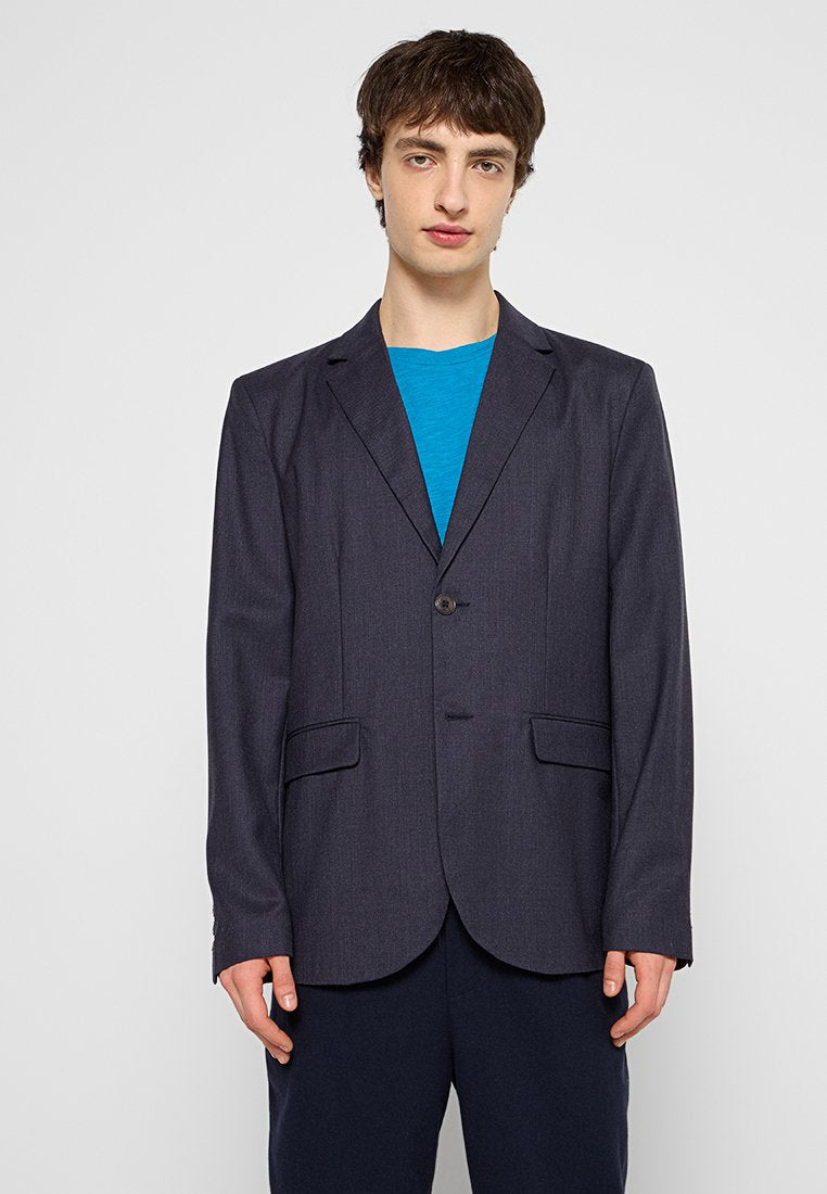 Marineblazer mit Ein-Knopf-Verschluss, Reverskragen und zwei vorderen Taschen, aus strukturiertem Stoff, kombiniert mit einem blauen T-Shirt.