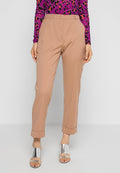 Beige maßgeschneiderte Hose mit hoher Taille, schmal zulaufenden Beinen und umgeschlagenen Säumen. Tragend mit einem lila Leopardenmuster-Oberteil und silbernen Sandalen.