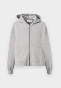 Grauer Kapuzensweatshirt mit einem durchgehenden Reißverschluss, das mit Nieten entlang der Ärmel und Kängurutaschen ausgestattet ist. Aus weichem Baumwollmaterial.