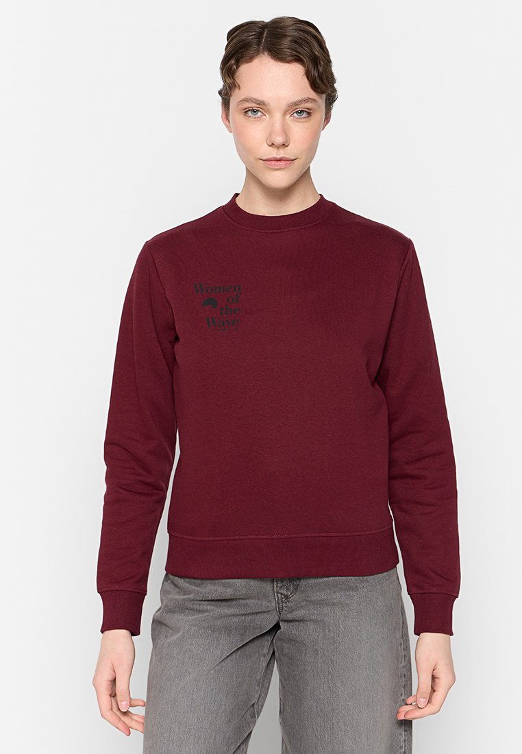 Burgunderfarbenes Sweatshirt mit Rundhals, langen Ärmeln und gerippten Bündchen. Auf der Brust befindet sich ein schwarzer grafischer Text "Frauen der Wellen".