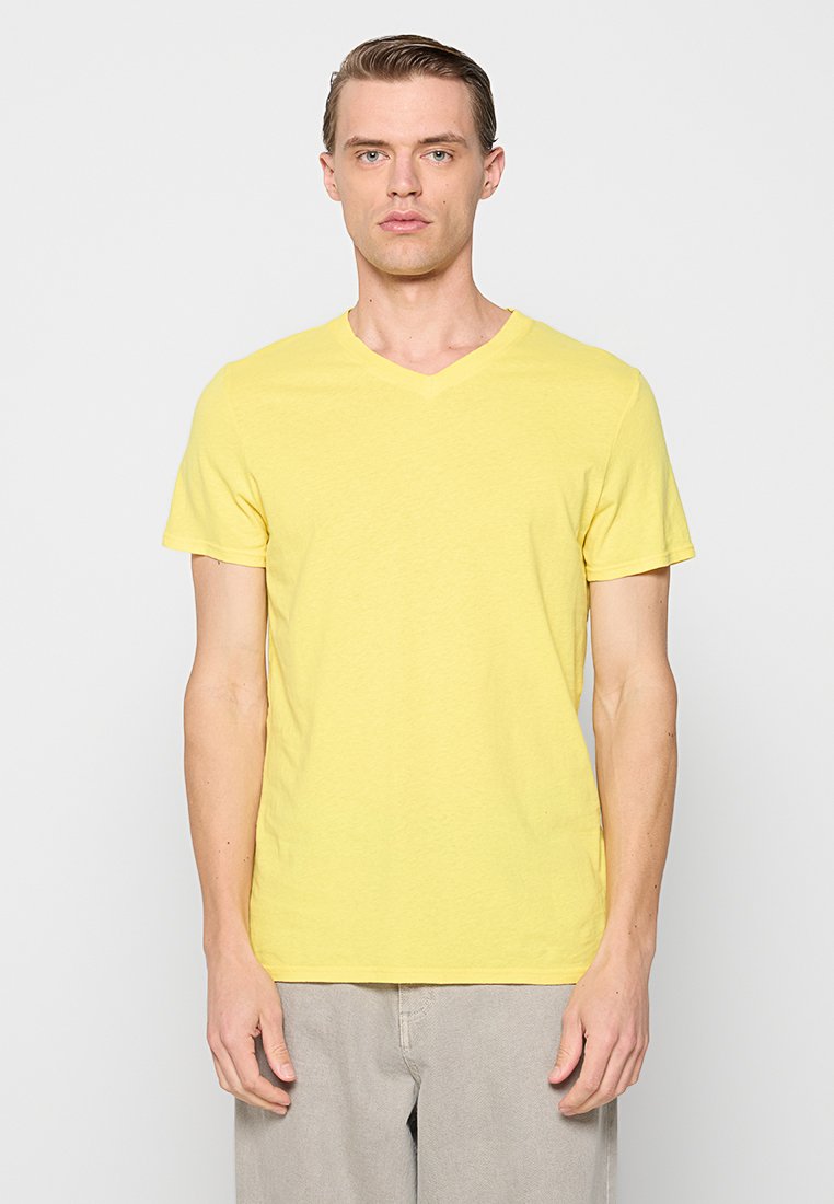 Gelbes Baumwoll-T-Shirt mit V-Ausschnitt und kurzen Ärmeln, weiche Textur und lockere Passform, vor einem weißen Hintergrund präsentiert.