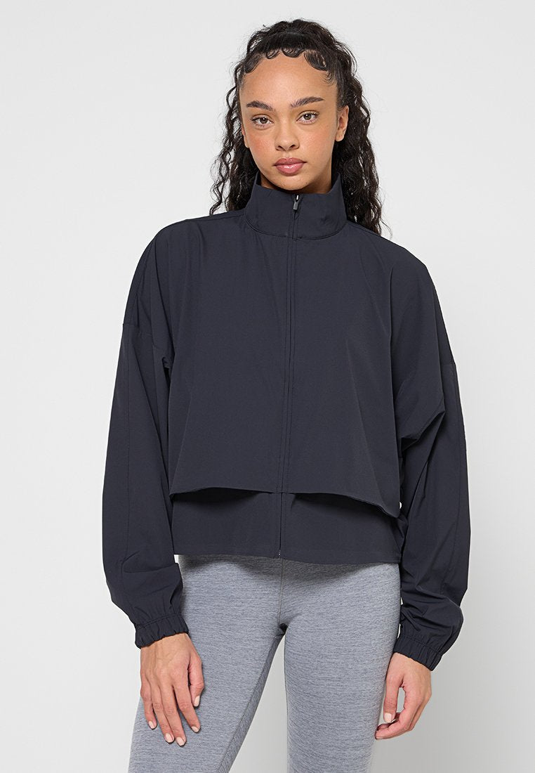 Schwarze, verkürzte Jacke mit hohem Kragen, Reißverschluss und übergroßen Ärmeln. Glatter Stoff mit elastischen Bündchen und minimalistisches Design.