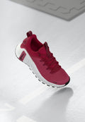 Roter Turnschuh mit strukturiertem Obermaterial, Schnürsenkeln und einer dicken weißen Sohle. Verfügt über eine kontrastierende schwarze Zehenkappe und ein Logo an der Seite.