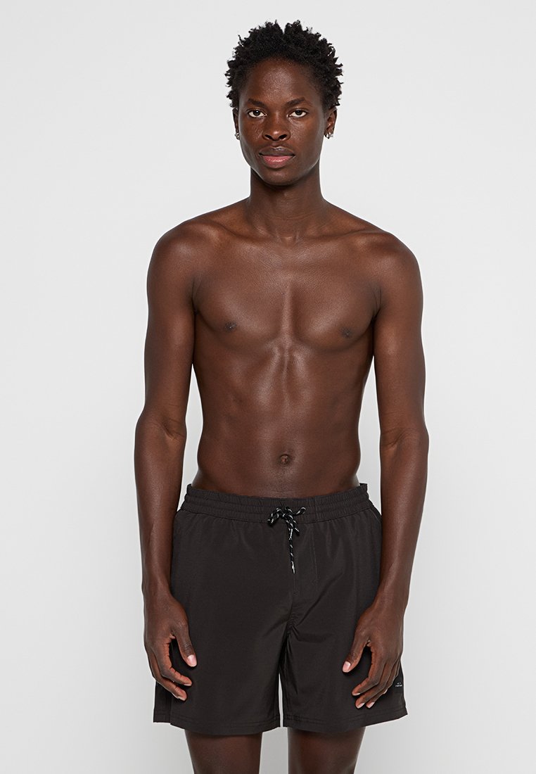 Schwarze Badehose mit elastischem Bund und Kordelzug, aus glattem Material. Ärmelloses Modell, das die Shorts frontal präsentiert.