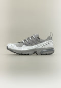 Grauer Sportschuh mit strukturiertem Obermaterial, reflektierenden Akzenten und gedämpfter Sohle. Verfügt über ein Schnürdesign und eine Zuglasche an der Rückseite.