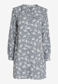Langärmliges Kleid in navyblau und weißem Karomuster, mit Rüschenausschnitt und floralen Akzenten, aus leichtem Stoff gefertigt.
