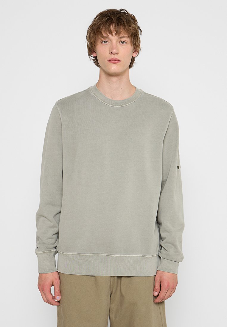 Hellgrüner Rundhals-Pullover mit langen Ärmeln, gerippten Bündchen und Saum. Verfügt über eine subtile Textur und ein Logo am linken Ärmel.