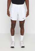 Athlet trägt weiße Nike-Sportshorts mit Logos, weiße Socken und weiße Laufschuhe, steht vor einem schlichten hellen Hintergrund.