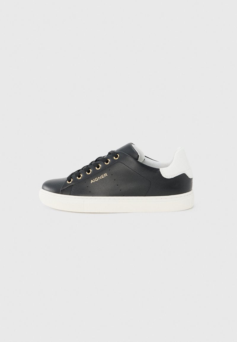 Schwarzer Ledersneaker mit weißer Ferse, goldenen Ösen, weißer Sohle und „AIGNER“-Logo an der Seite, im Seitenprofil vor grauem Hintergrund gezeigt.