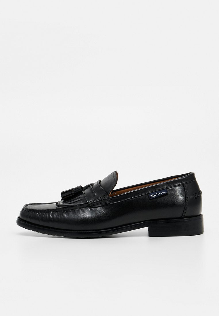 Schwarzer Leder-Tasselloafer für Herren mit niedrigem Absatz, genähtem Mokassinfuß und Markenetikett an der Seite.