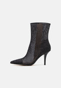 Schwarze Knöchelstiefel mit spitz zulaufender Zehe, versehen mit einem Spitzenüberzug und transparentem Design. Der dünne Stiletto-Absatz unterstreicht die elegante Silhouette.