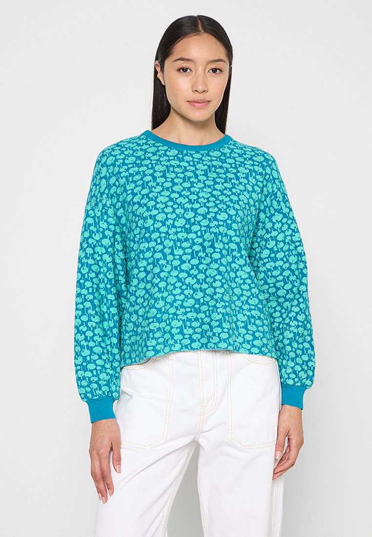 Gecropter Pullover in leuchtendem Türkis mit einem gemusterten Overlay in helleren Türkistönen. Verfügt über lange Ärmel und gerippte Bündchen.