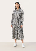 Langärmeliges, knöpfbares Kleid im schwarz-weißen abstrakten Muster; tailliertes Design; leichtes Material mit fließendem Rock; kombiniert mit weißen Sneakers.