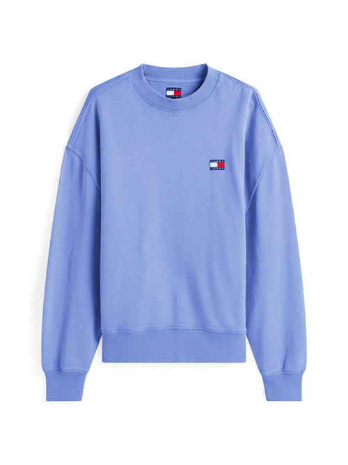 Hellblauer Pullover mit geripptem Rundhalsausschnitt, überschnittenen Schulternähten und einem kleinen Logo-Patch in den Farben Rot, Weiß und Blau.