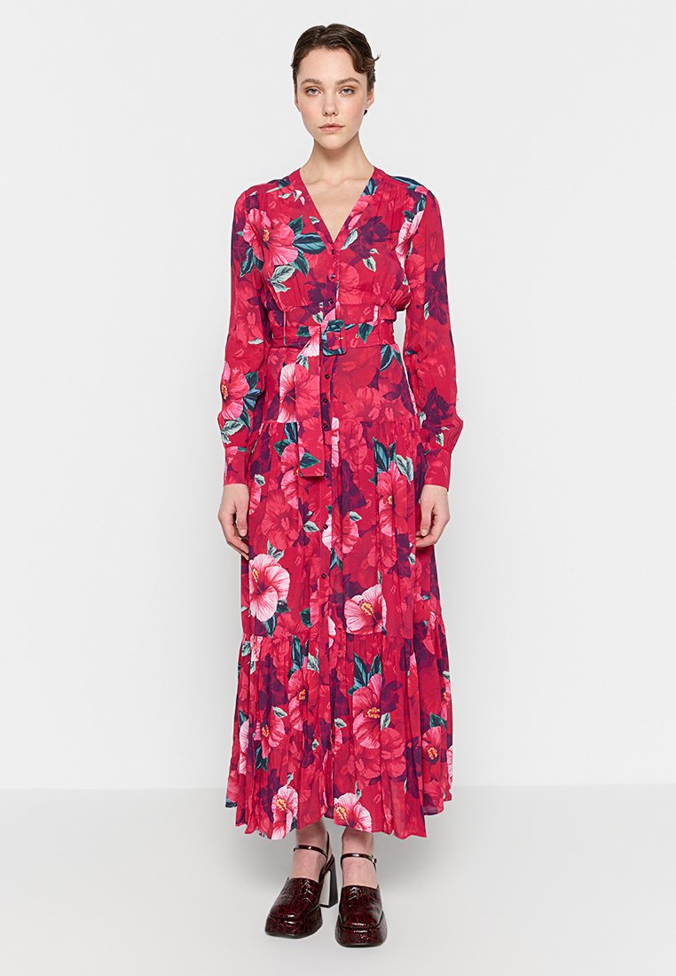 Blumenmuster-Kleid mit langen Ärmeln und V-Ausschnitt, tailliertem Bund und gestuftem Rock in leuchtendem Pink, das große rote und grüne Blumenmuster aufweist.